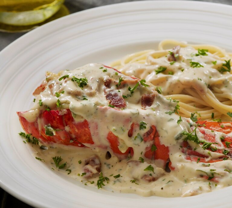 Ein weißer Teller mit Spaghetti der Carbonara-Soße und einem Hummer der mit Soße bedeckt ist. | © Gettyimages/ LauriPatterson