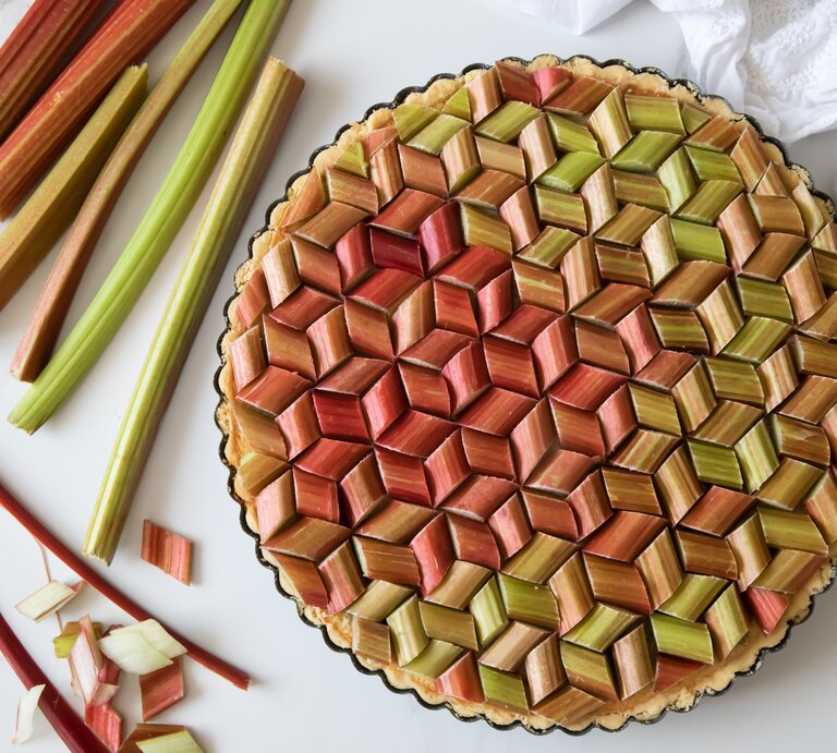 Eine vegane Erdbeer-Rhabarber-Tarte in der Draufsicht, daneben liegen Rhabarberstangen. | © Shutterstock/ rontav