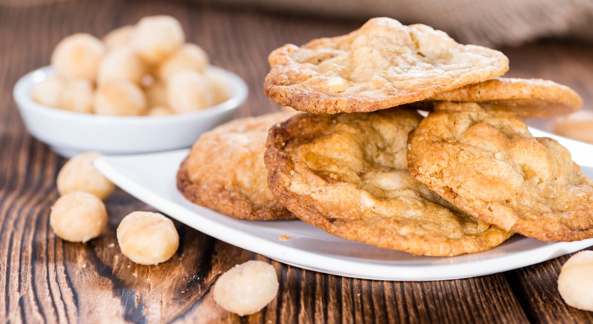 Mehrere Cookies auf einem weißen Teller und Holztisch aus seitlicher Perspektive fotografiert.