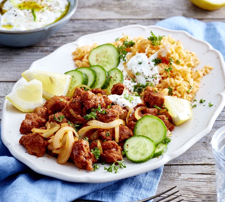 Auf einem Teller ist eine Veggie-Gyros-Platte mit Gurken, Zitrone und Reis angerichtet. | © EAT CLUB / Isabell Triemer