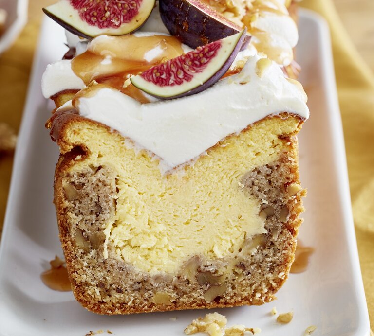 Angeschnittener Feigen-Walnuss-Kuchen auf weißem Teller, im unscharfen Hintergrund Walnüsse und ein gelbes Küchentuch.  | © EAT CLUB / Isabell Triemer 