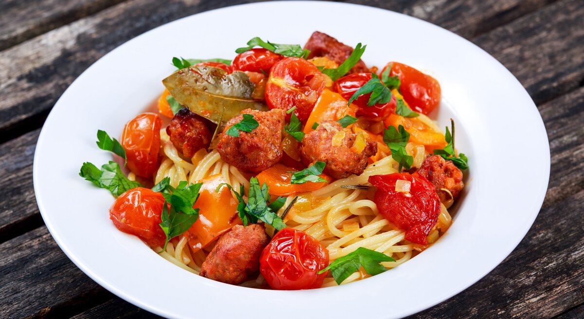 Ein weißer Teller mit dem Pastagericht auf dunklem Holzuntergrund.