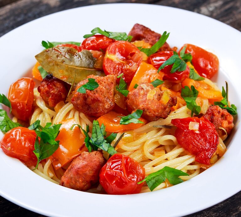 Ein weißer Teller mit dem Pastagericht auf dunklem Holzuntergrund. | © Shutterstock/ DronG 