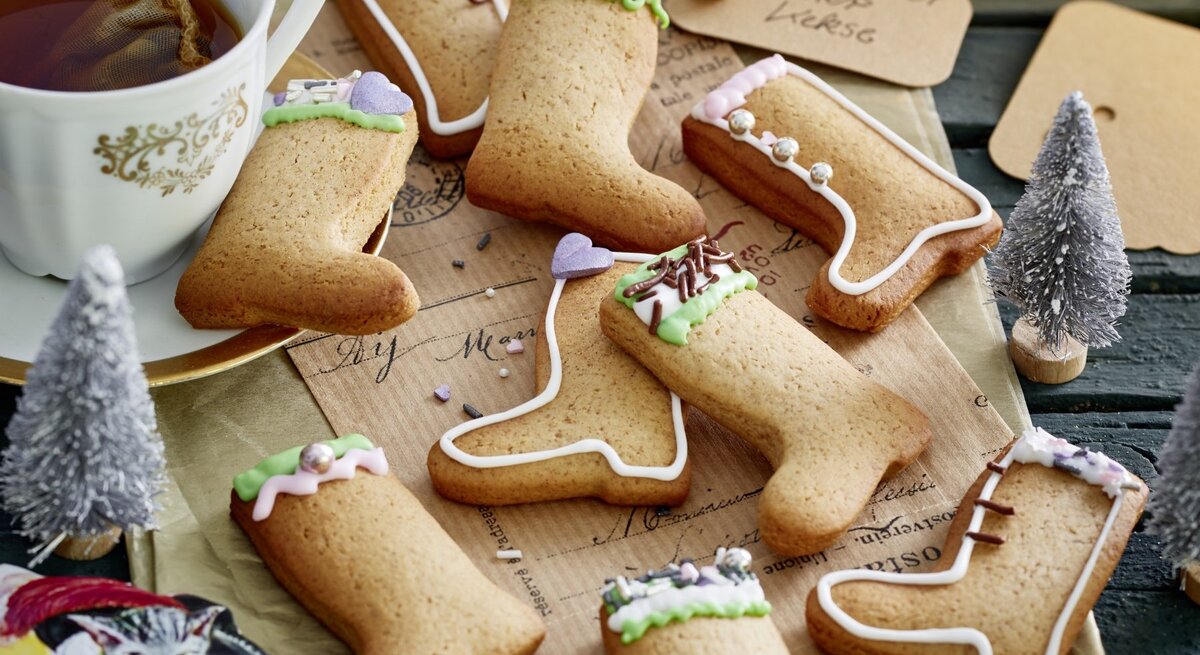 Auf einem Weihnachtstisch liegen meherer Gestiefelter-Kater-Kekse. Sie sind mit buntem Zuckerguss dekoriert.