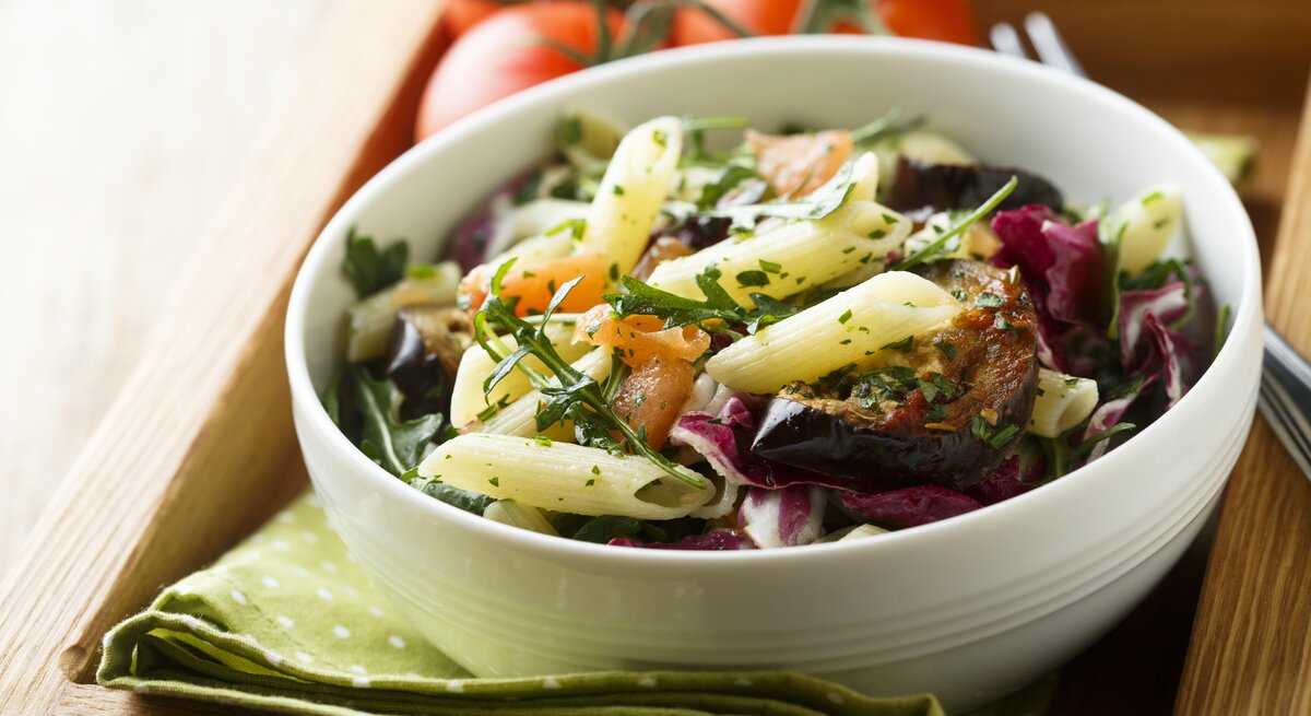 Eine Schüssel Nudelsalat mit Aubergine, Rucola und Minze.