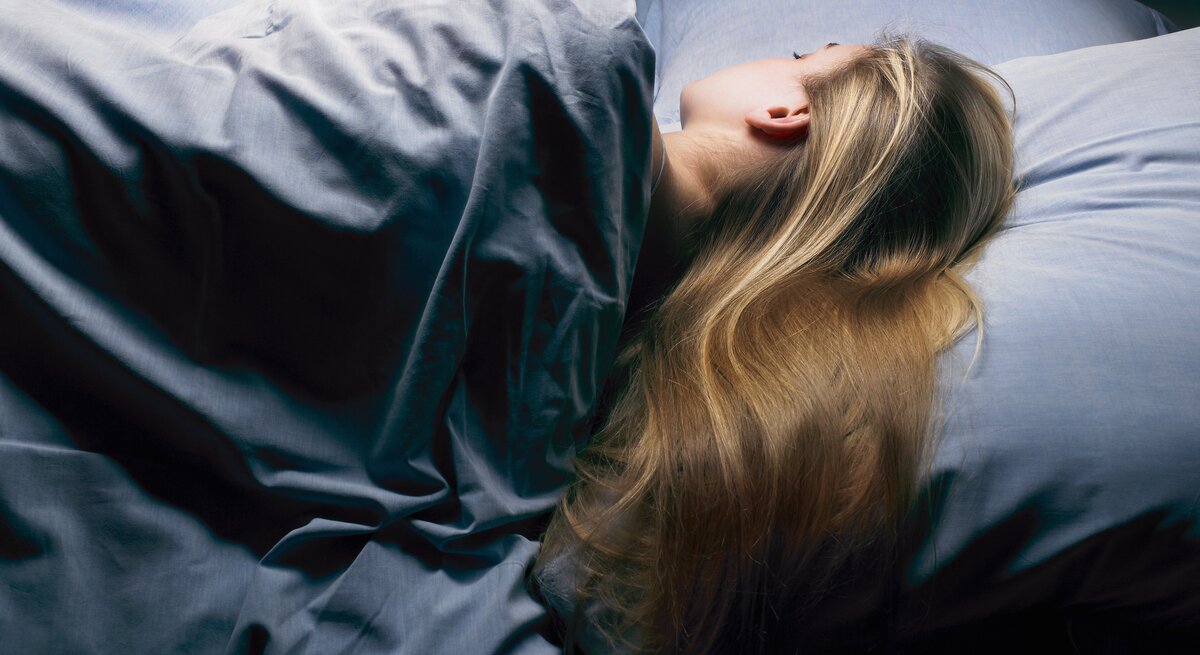 Frau schläft seitlich im Bett.