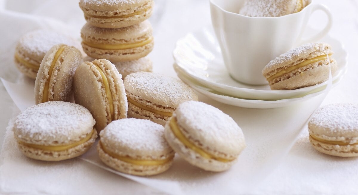 Zimt-Eierlikör-Macarons, serviert auf einem weißen Küchentuch mit einer Tasse Kaffee. 