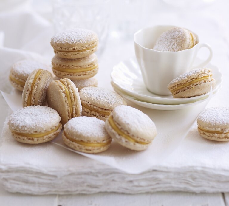 Zimt-Eierlikör-Macarons, serviert auf einem weißen Küchentuch mit einer Tasse Kaffee.  | © StockFood / Are Media
