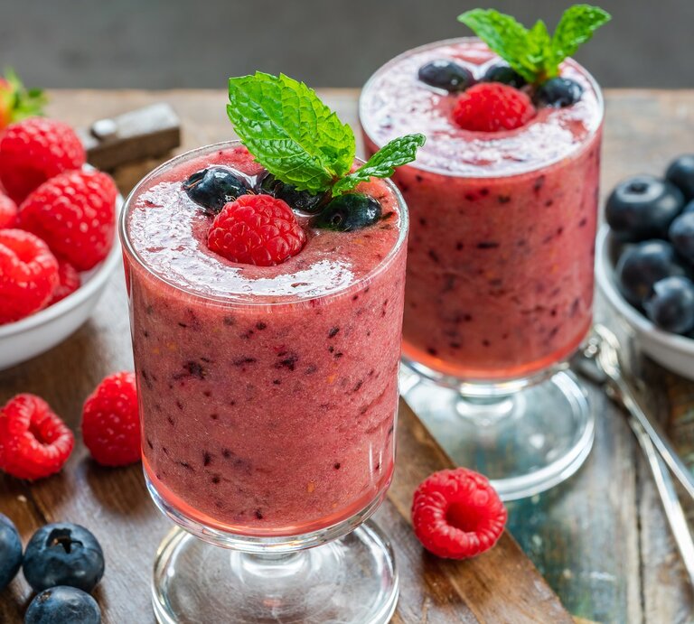 Zwei Gläser mit Beeren-Matcha-Smoothie auf einem Holztisch. | © Shutterstock/BBA Photography