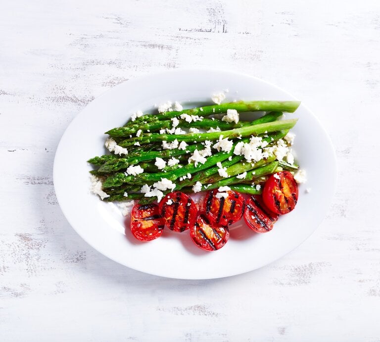 Ein Teller gegrillter Spargel mit Zitrone und Feta sowie gegrillten Tomaten in der Draufsicht. | © Adobe Stock/ B.G. Photography
