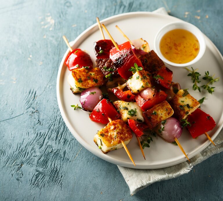 4 Tofu-Grillspieße mit Gemüse auf einem Teller, auf dem auch eine Schale mit Dip steht.  | © Adobe Stock/ marysckin