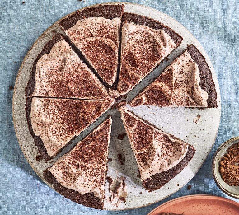 Auf einem Teller liegt ein Keto-Schokoladenkuchen. Er ist mit Kakaopulver bestreut. | © StockFood / Immediate Media / Good Food