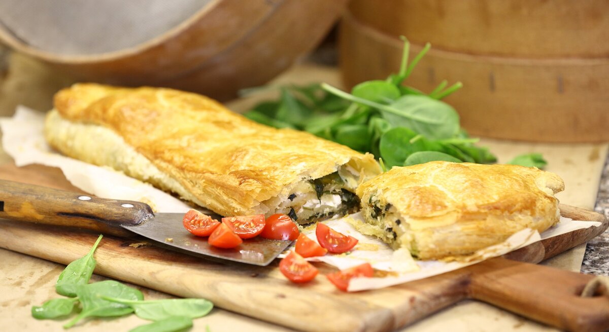 Spinat-Strudel mit Feta und Knoblauch / Holzbrettchen / Untergrund Holz / frische Basilikumblätter, Tomaten