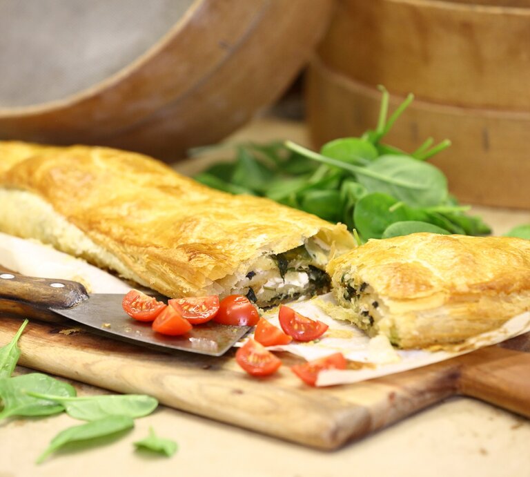 Spinat-Strudel mit Feta und Knoblauch / Holzbrettchen / Untergrund Holz / frische Basilikumblätter, Tomaten | © StockFood/Raider