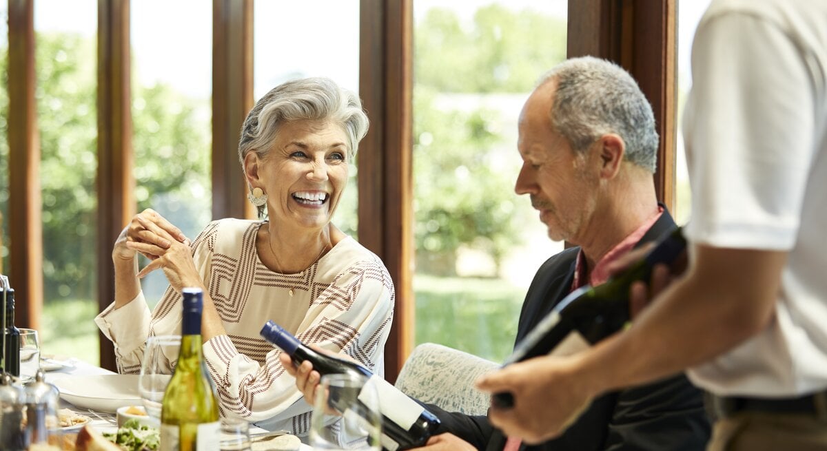 Zwei ältere Personen im Restaurant beim Weinprobieren.