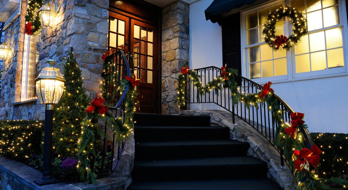 Die Fenster und Türen eines Hauses sind mit Lichterketten behangen.