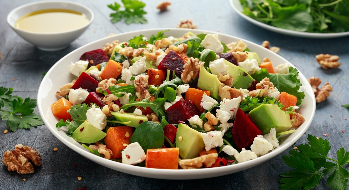 Ein weißer tiefer Teller mit einer Kürbis-Bowl mit Avocado und Feta.