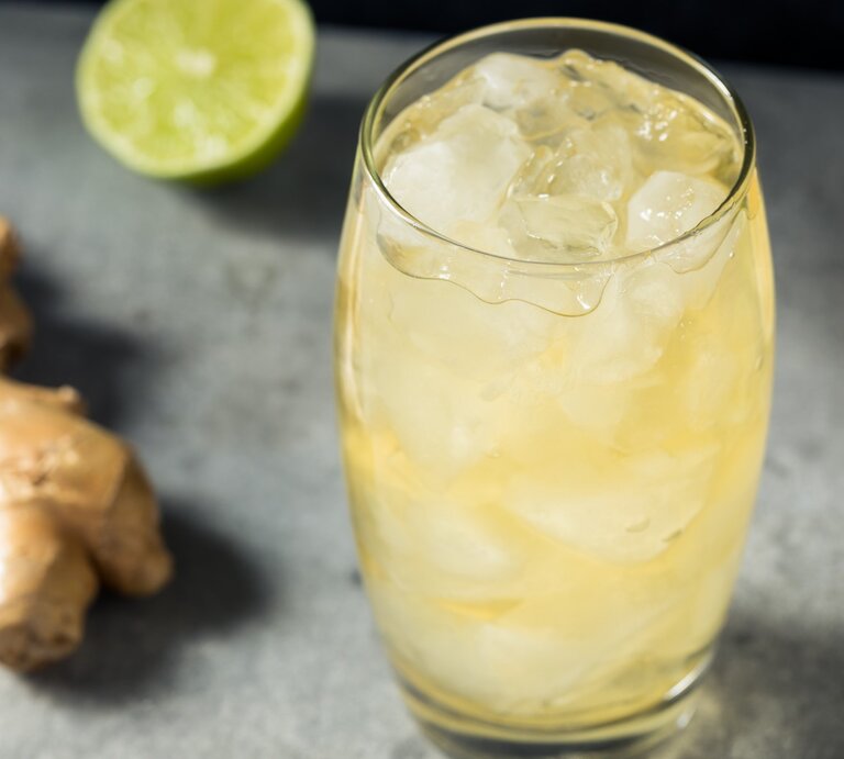 Ein Glas mit Ingwerlimonade auf einem grauen Untergrund. Daneben eine halbe Limette und eine halbe Zitrone sowie eine Ingwerknolle. | © Gettyimages/ bhofack2