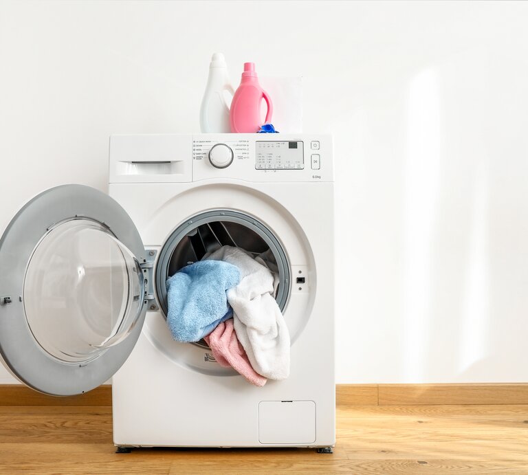 Eine Waschmaschine mit geöffneter Tür. Darin liegt gewaschene Wäsche. | © shutterstock/LumenSt