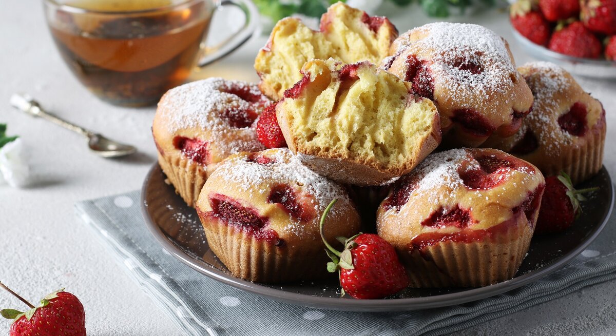 Mehrere Ricotta-Erdbeer-Muffins / ganze und halbiert Backwaren / Teller / Honig im Glas / Löffel / Nahaufnahme / Frontallsicht | © AdobeStock/Anzhela