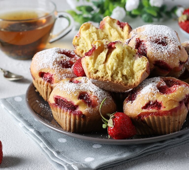 Mehrere Ricotta-Erdbeer-Muffins / ganze und halbiert Backwaren / Teller / Honig im Glas / Löffel / Nahaufnahme / Frontallsicht | © AdobeStock/Anzhela