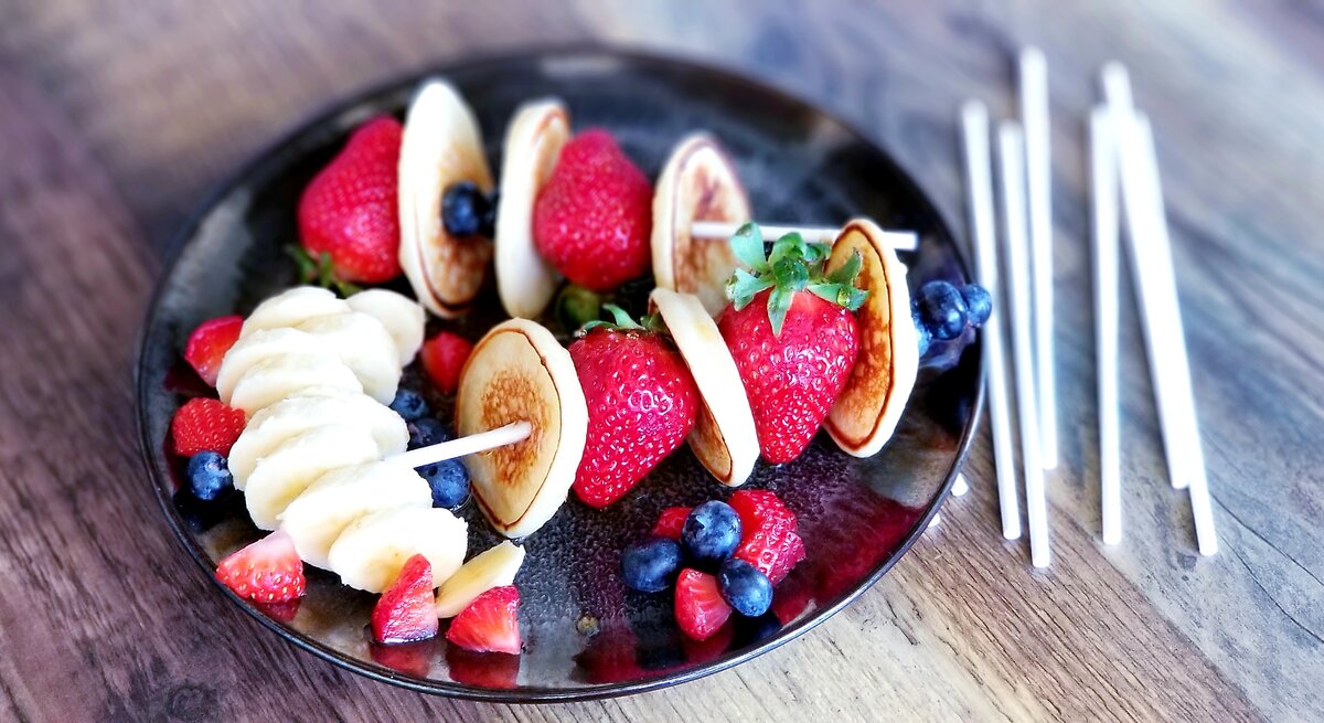 Zwei Pfannkuchen-Spieße mit Erdbeeren /  Teller / Holzspieße / Nahaufnahme Draufsicht