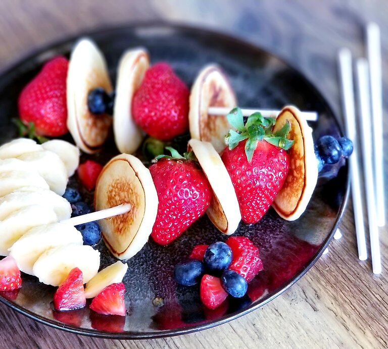 Zwei Pfannkuchen-Spieße mit Erdbeeren /  Teller / Holzspieße / Nahaufnahme Draufsicht | © Getty Images/ Vicky Hadley
