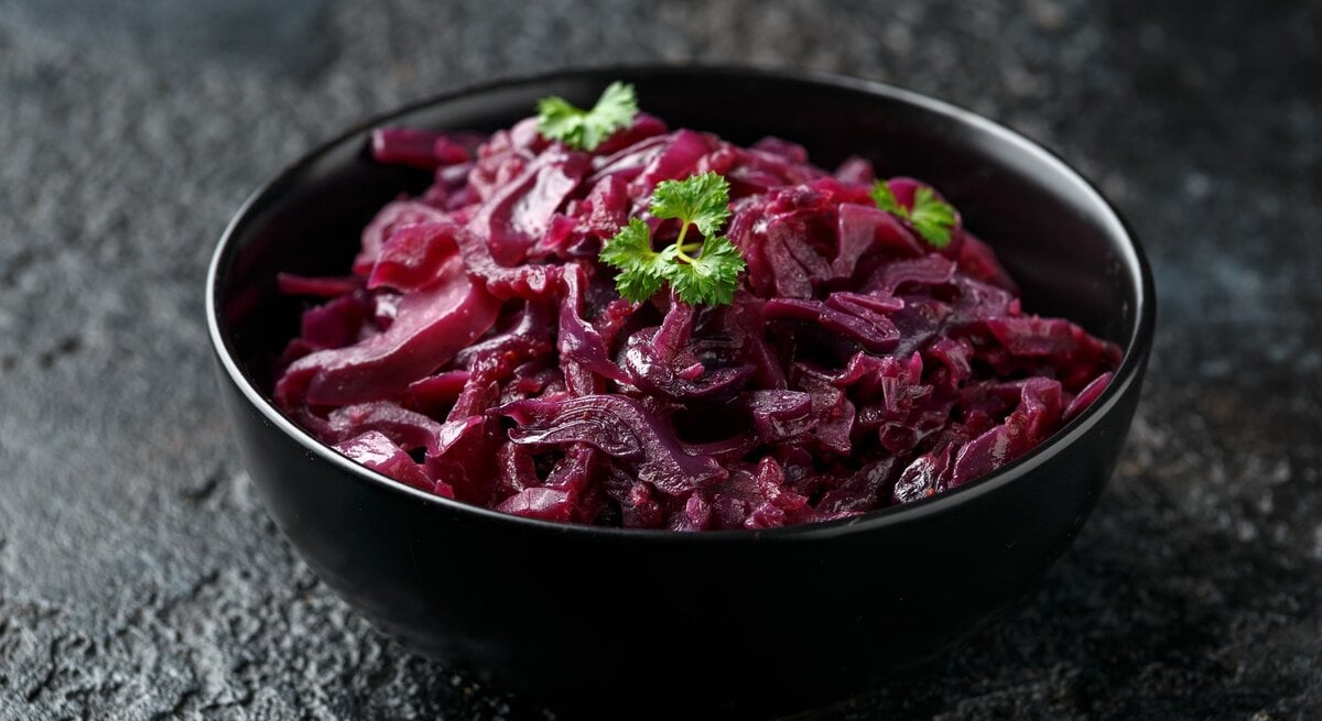 Eine schwarze Schale mit Rotkohl auf einem dunklen Tisch.