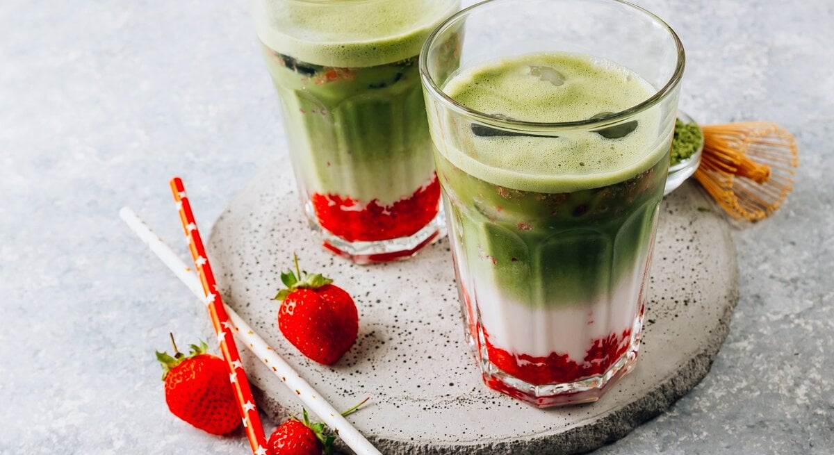 Zwei Gläser mit Matcha-Erdbeer-Latte auf einer Baumscheibe. | © Shutterstock/Julia Mikhaylova