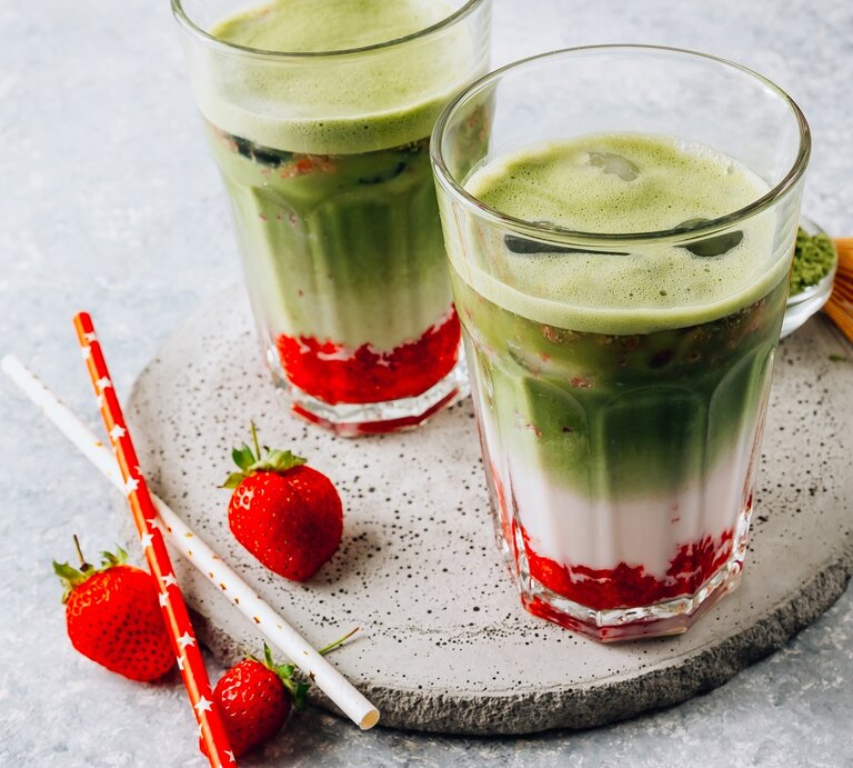 Zwei Gläser mit Matcha-Erdbeer-Latte auf einer Baumscheibe. | © Shutterstock/Julia Mikhaylova