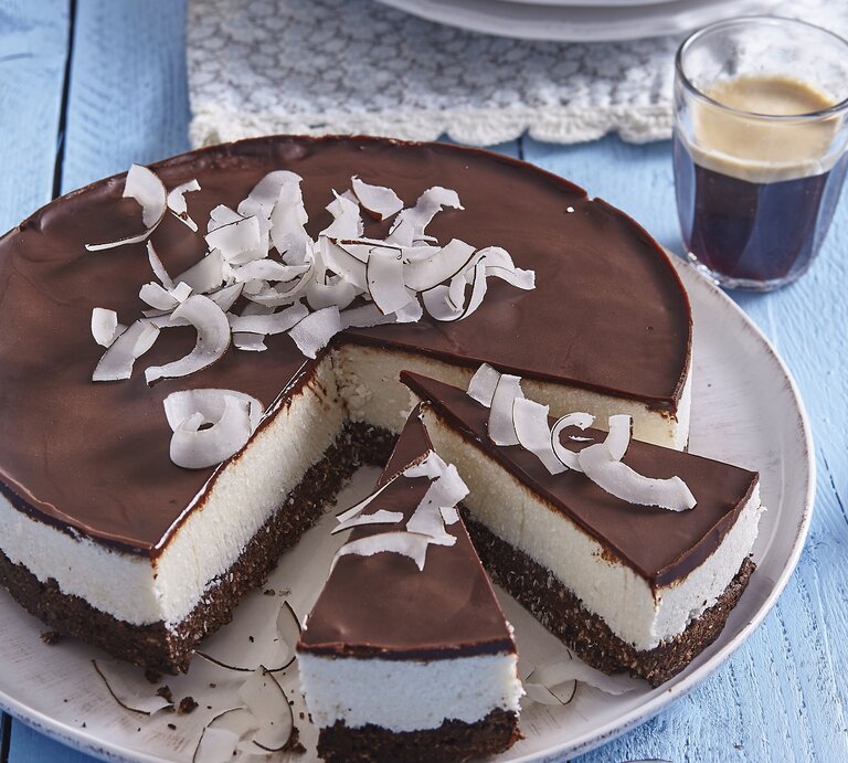 Bounty-Torte mit Kokosraspeln / Glas mit Kaffee / Untergrund Holz / Draufsicht schräg | © StockFood / Profimedia