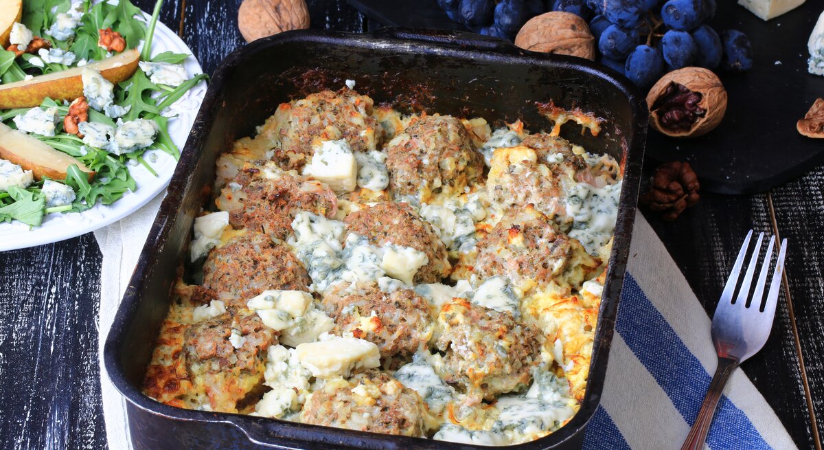 Herzhafter Hackbällchen-Auflaufs in cremiger Gorgonzola-Soße, serviert in einer schwarzen, ofenfesten Form. Die Hackbällchen sind gleichmäßig in der goldbraunen, cremigen Käsesoße verteilt.