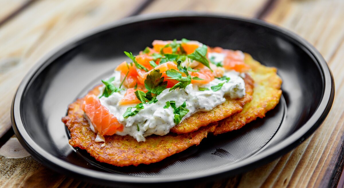 Gebratener Kartoffelpuffer mit Quark und einer Scheibe Räucherlachs belegt. 