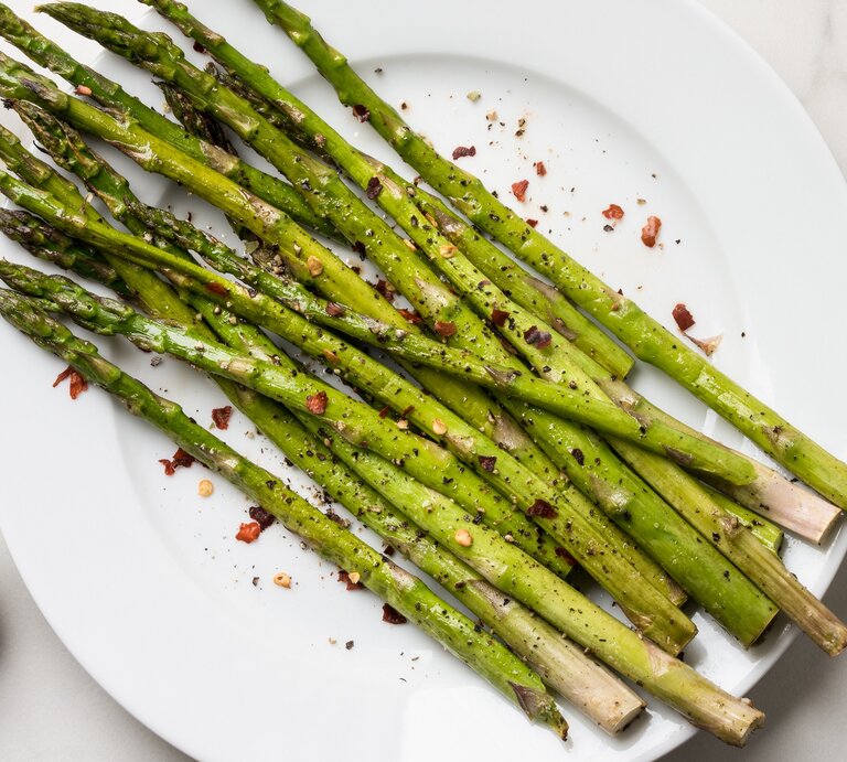 Ein Teller mit Knoblauch-Zitronen-Spargel. daneben eine Gabel, alles Draufsicht. | © Adobe Stock/ Michelle