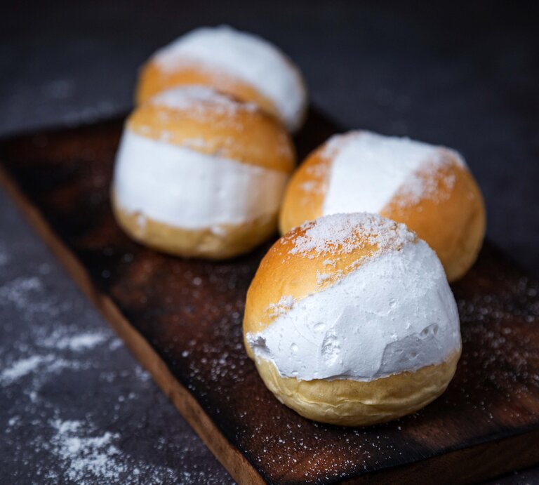 Vier der gefüllten Milchbrötchen auf einem dunklem Holzbrett mit schwarzem Unter- und Hintergrund. | © Shutterstock/ nawapol naoniao