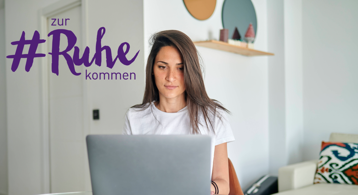 Eine junge Frau sitzt konzentriert an einem gläsernen Tisch und arbeitet an ihrem Laptop. Sie trägt ein weißes T-Shirt und hat lange dunkle Haare. Im Hintergrund ist ein modern eingerichtetes Zimmer mit hellen Wänden und zeitgenössischer Dekoration zu sehen. Auf dem Laptop ist der Schriftzug "#zur Ruhe kommen" zu sehen.
