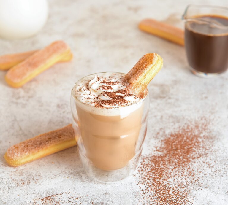 Ein Glas mit Tiramisu-Latte neben einem Löffelbiskuit. | © Shutterstock/Pixel-Shot