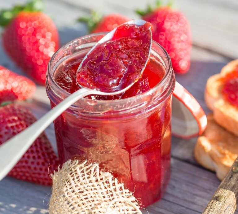 Ein Glas Erdbeer-Kokos-Marmelade mit einem Löffel/ drumherum frische Erdbeeren / Toast / Marmelade | © Getty Images/ Eduardo Gonzalez Diaz / EyeEm