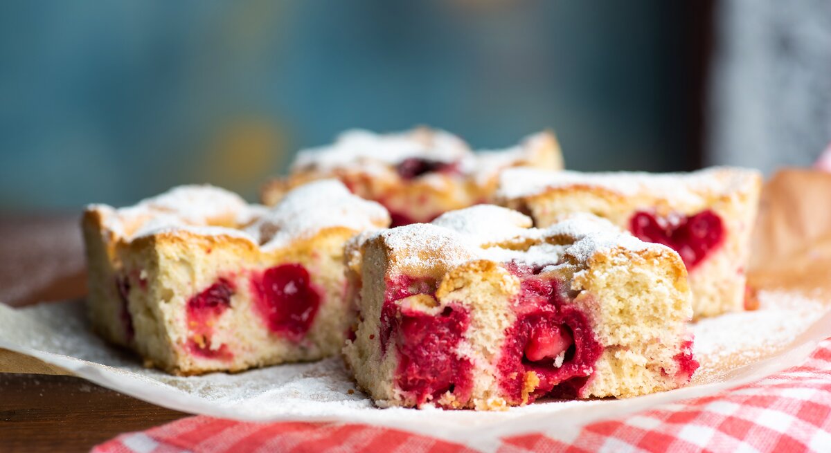 Süßkirsch-Kuchen auf Küchenpapier vor blauem Hintergrund. 