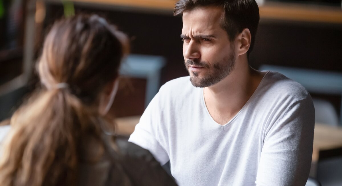 Mann und Frau sitzen sich in einem Café gegenüber. Der Mann hat einen besorgten oder verwirrten Gesichtsausdruck.