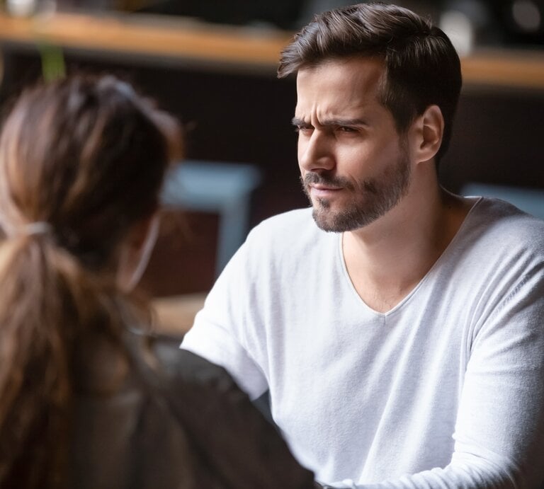 Mann und Frau sitzen sich in einem Café gegenüber. Der Mann hat einen besorgten oder verwirrten Gesichtsausdruck. | © Shutterstock / fizkes