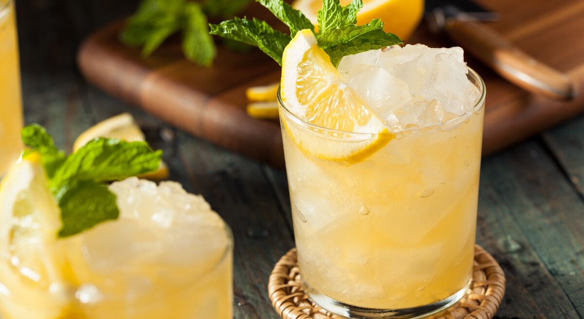 Ein Glas mit dem Dry Limoni auf einem Holztisch mit Zitrone und Minze.