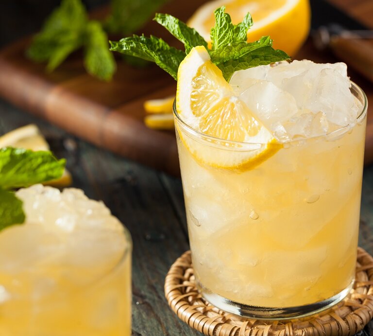 Ein Glas mit dem Dry Limoni auf einem Holztisch mit Zitrone und Minze. | © Shutterstock/Brent Hofacker