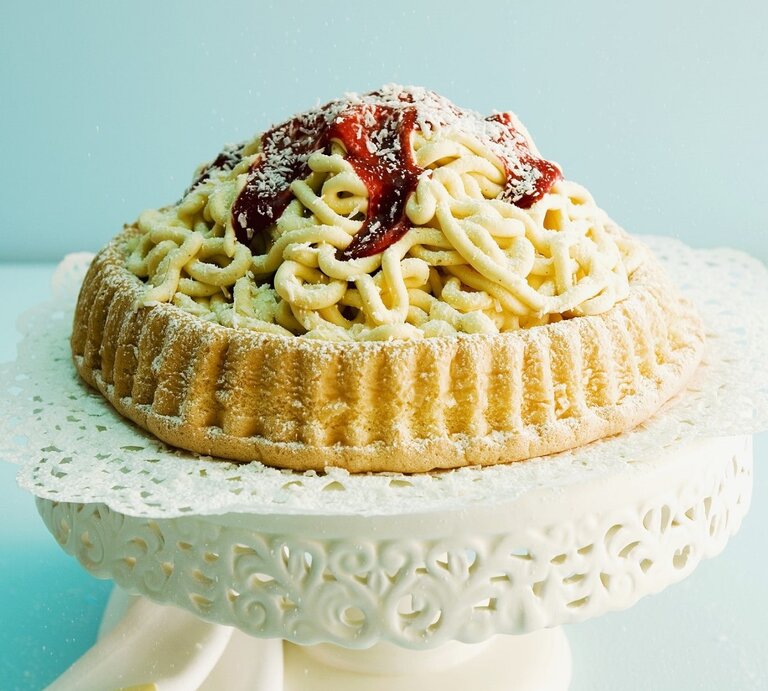 Auf einem Tortenteller steht eine Spaghettieistorte. Sie ist mit Johannisbeergelee und Puderzucker überzogen.  | © StockFood / Wissing, Michael