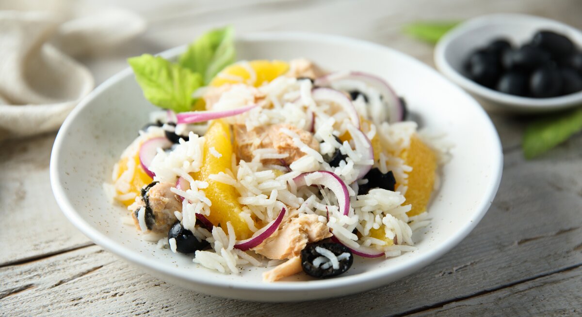 Reissalat mit Thunfisch und Mandarine auf weißem Teller. 