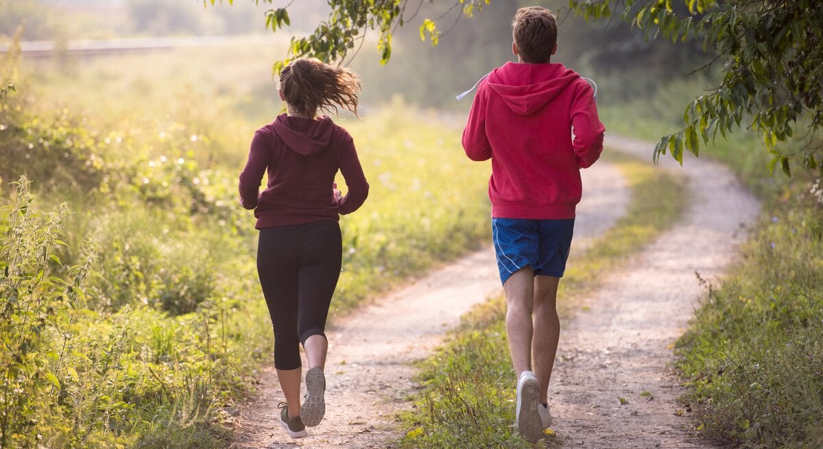 Ein junges Paar joggt über einen Feldweg.