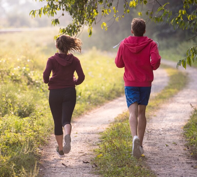 Ein junges Paar joggt über einen Feldweg. | © Shutterstock/dotshock