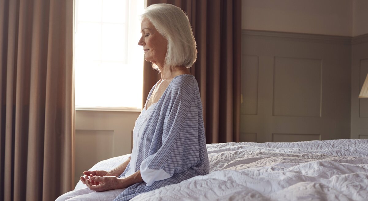Eine Dame startet achtsam mit Meditation in den Tag.
