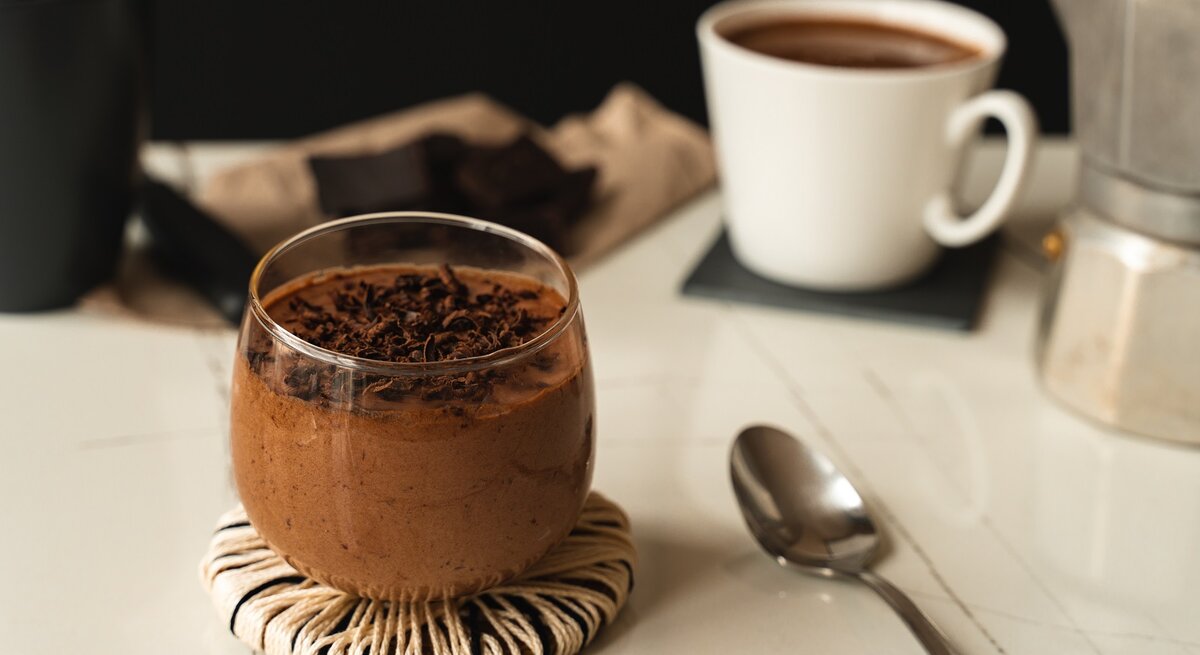 Ein Glas mit Schoko-Espresso-Mousse auf einem weißen Tisch.