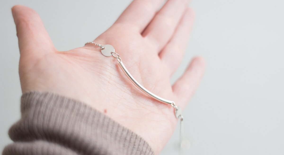 Ein silbernes Armband liegt auf einer ausgestreckten Hand.